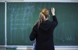 Das Bild zeigt eine Lehrerin vor einer Schultafel. Foto: DGUV